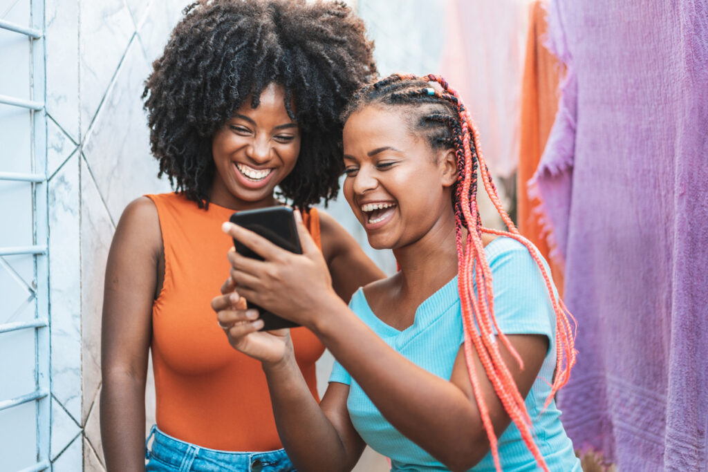Two African-American Females Laughing and Smiling at Something Happening on Their Phone