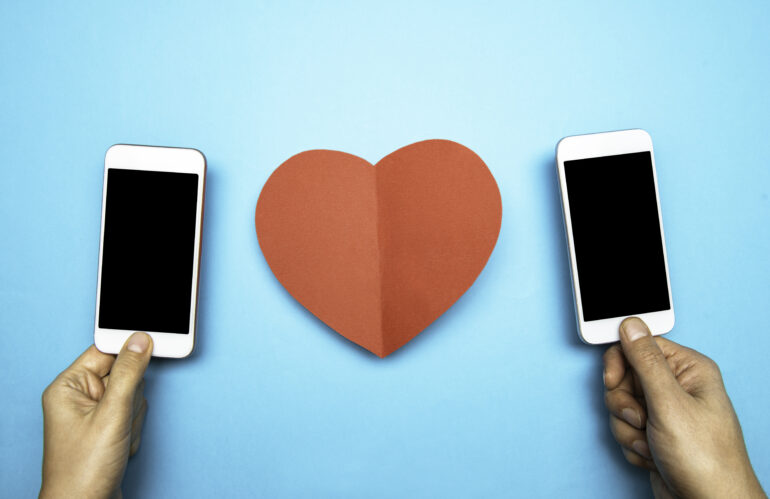 Two people holding cell phones with a heart in between them
